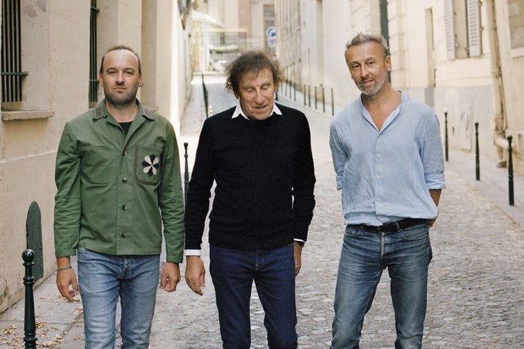 Alain Souchon et ses fils marchent dans une ruelle pavée