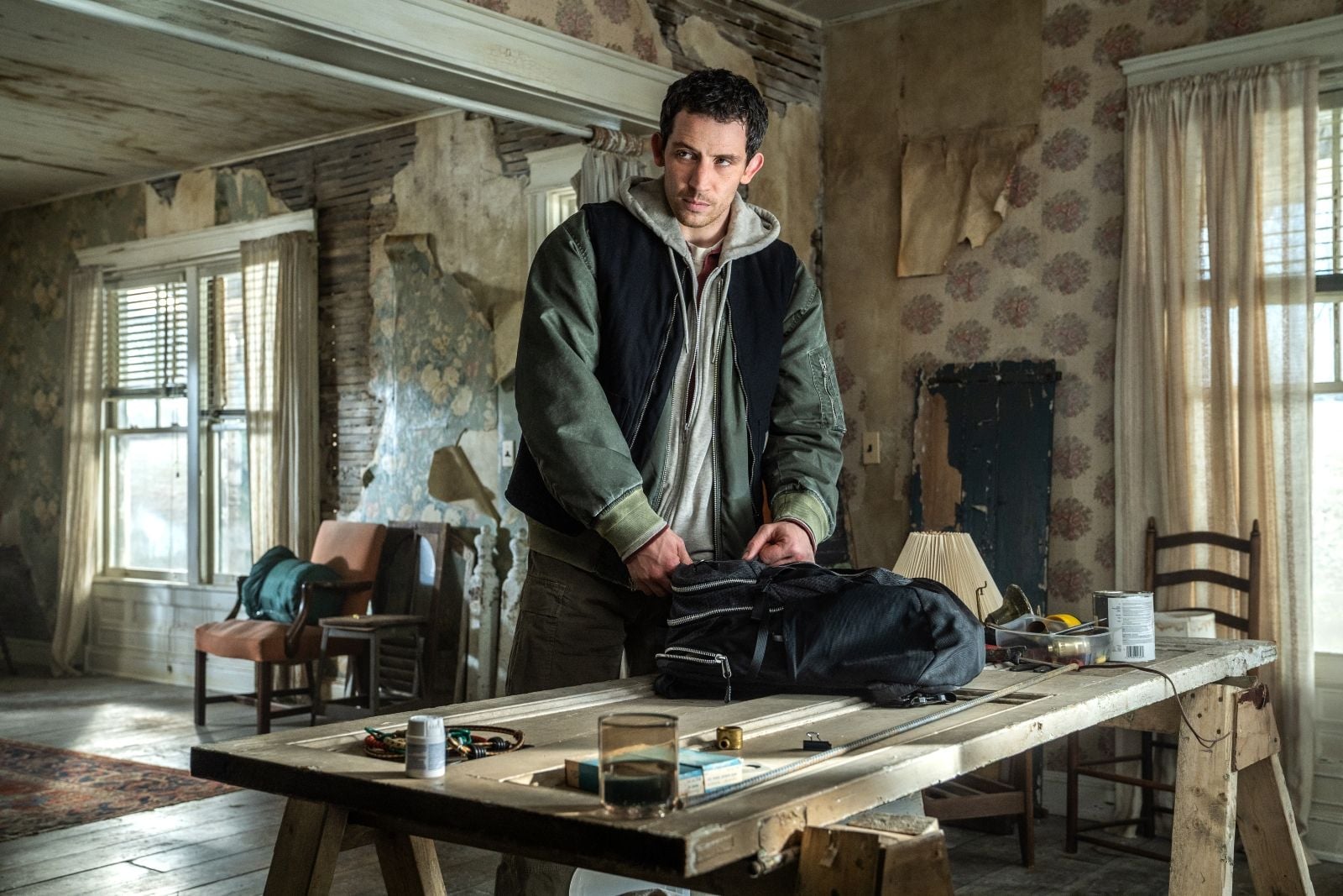Scène du film Disclosure Day, un homme prépare un sac dans une maison délabrée