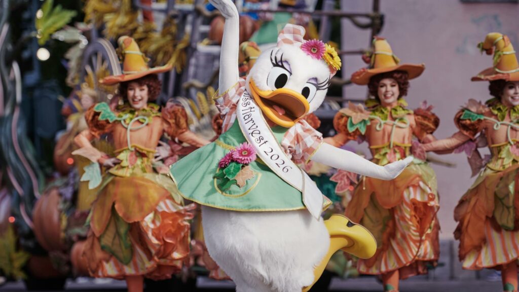 Daisy en tenue d'automne, entourée de danseuses coiffées de chapeaux de sorcière, pendant le Festival Halloween Disney