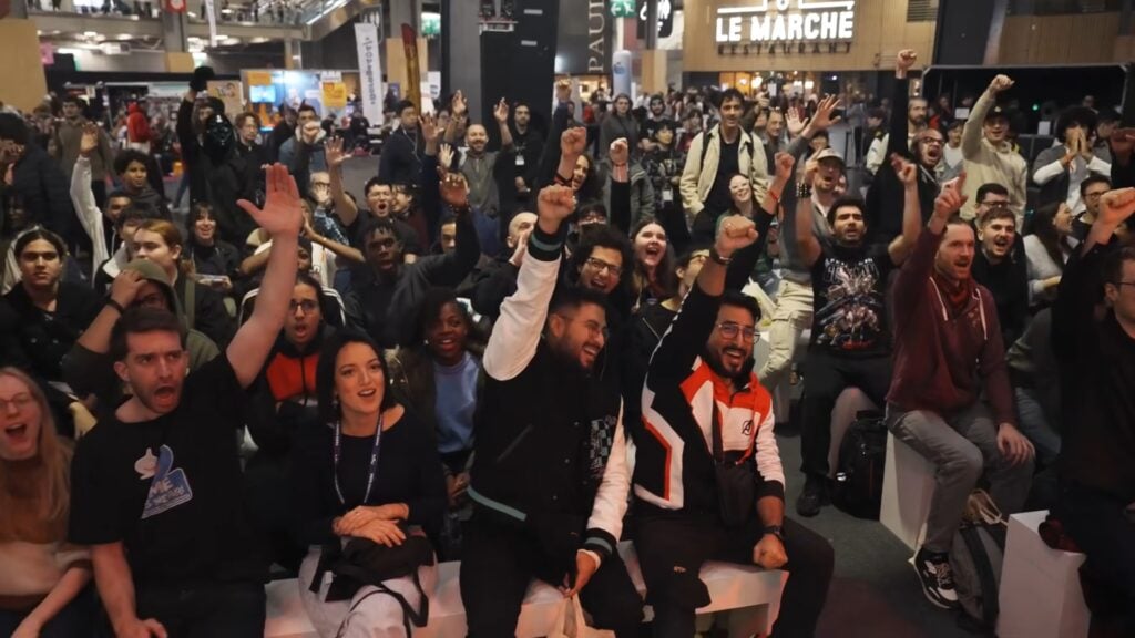 Des visiteurs bras levés et poings serrés, en pleine ovation sur le stand Capcom de la Paris Games Week, à Paris Expo