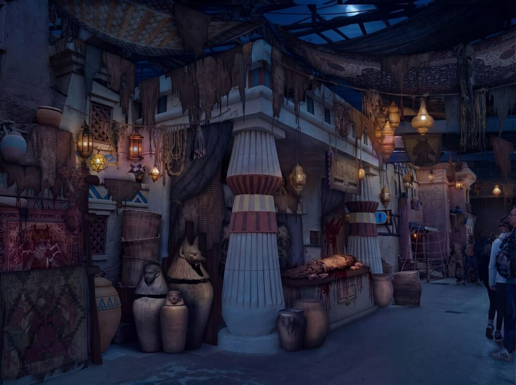 Une ruelle du Souk Égyptien plongée dans la nuit, entre colonnes peintes, jarres et lanternes