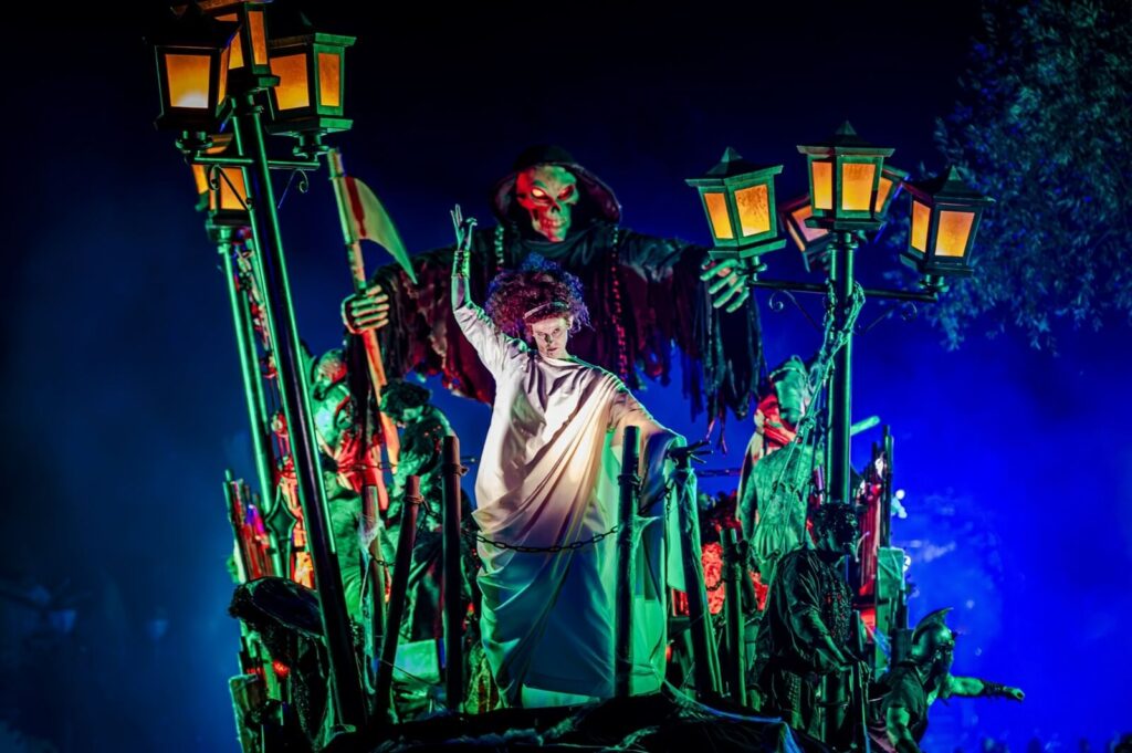 Un char lugubre éclairé de vert, de rouge et de bleu, chargé de monstres et de lanternes, pendant le Défilé des Monstres