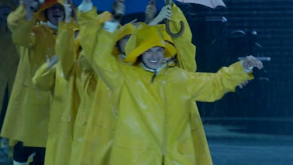La troupe en cirés jaunes sous la pluie dans Singin' in the Rain au Théâtre du Lido